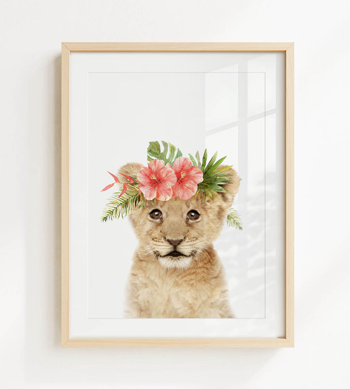 A young lion cub wearing a floral crown of pink and green flowers.