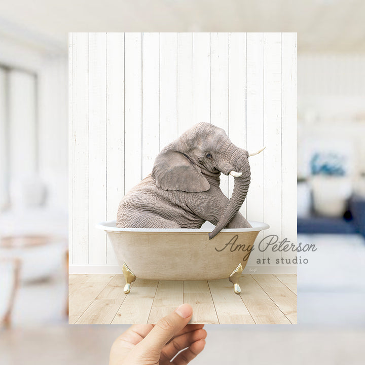 a hand holding a photo of an elephant in a bathtub