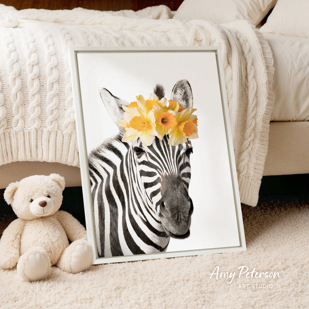 A framed photograph of a zebra wearing a yellow flower crown is displayed on a white bedspread, accompanied by a teddy bear.