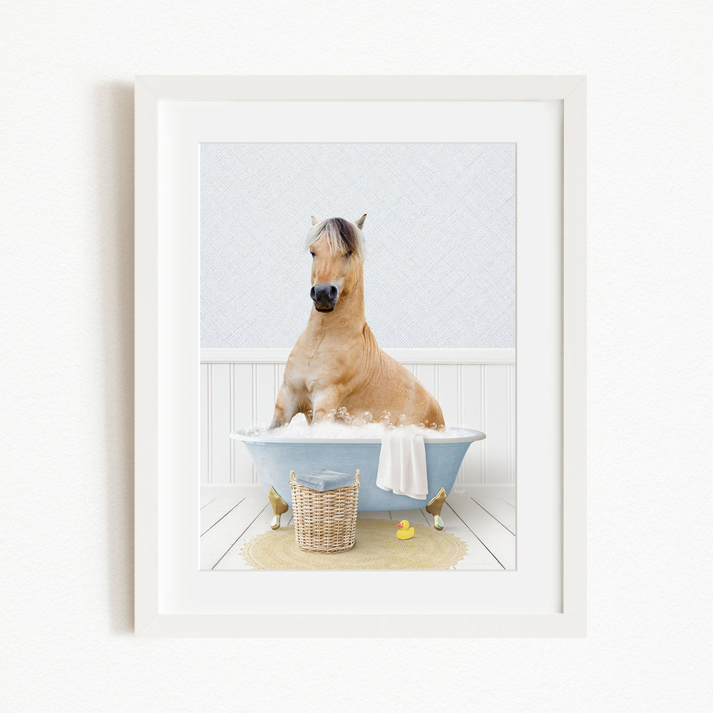 A light brown horse is sitting in a blue bathtub filled with water, surrounded by a yellow rubber duck and a basket.