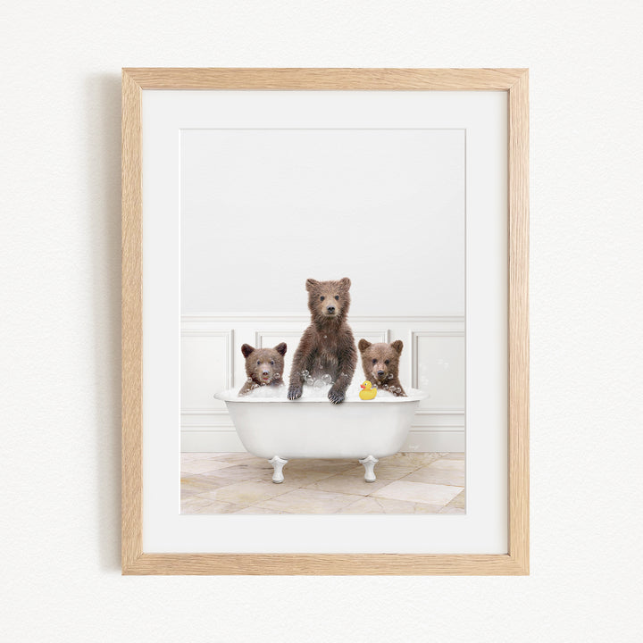 A framed image of three bears sitting in a white bathtub, with one bear holding a rubber duck.