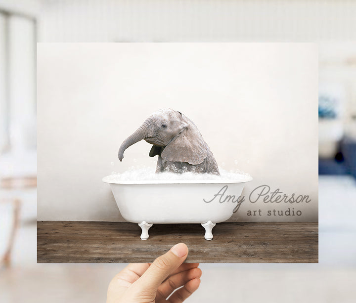 a person holding up a card with an elephant in a bathtub