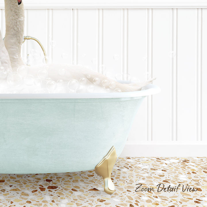A white bathtub filled with bubbles, with a gold-colored claw-foot design, and a person sitting in the tub.