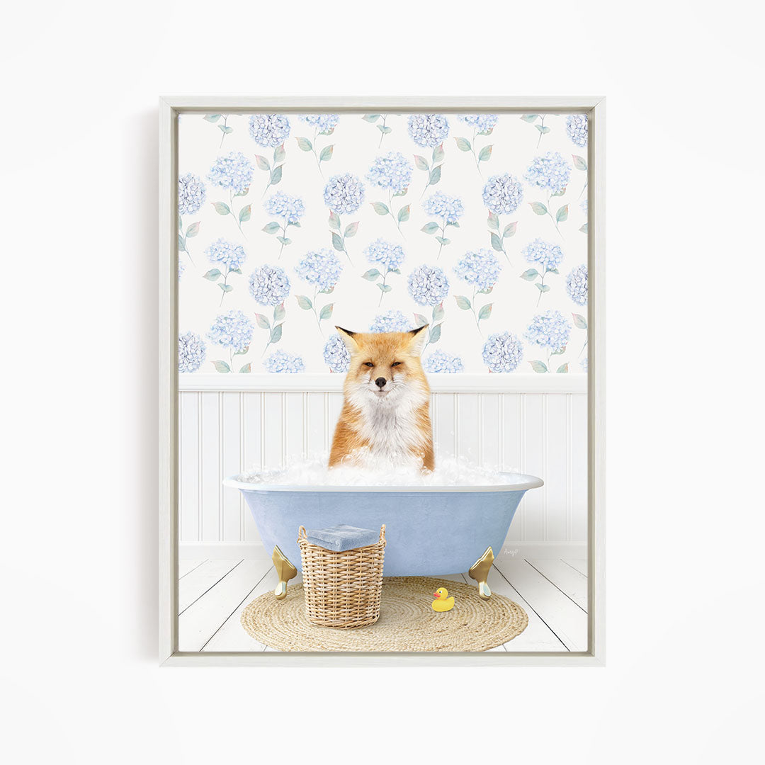 A fox is sitting in a blue bathtub filled with water, surrounded by a wicker basket and a yellow rubber duck.