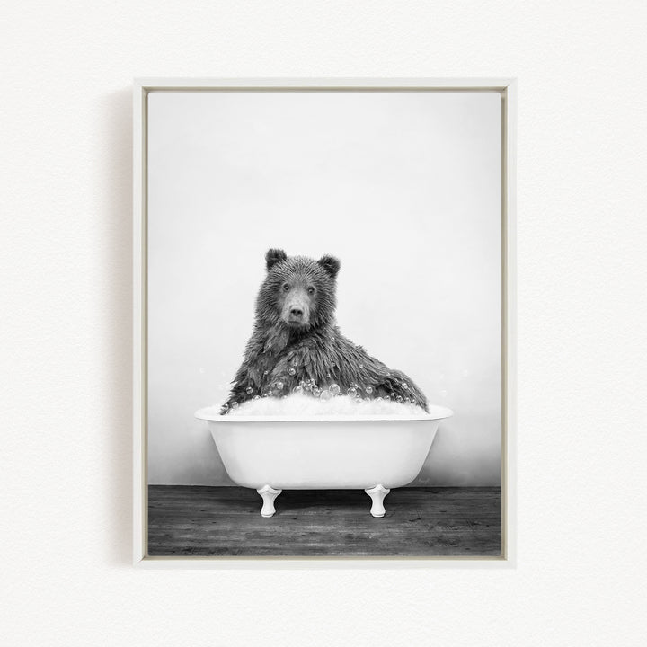 A black and white photograph of a bear sitting in a bathtub filled with water.