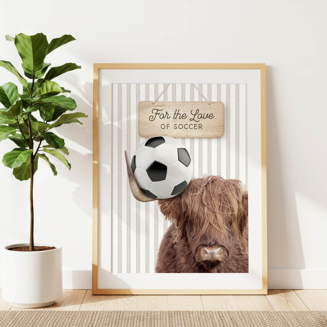 a framed poster with a soccer ball and a cow's head, along with a wooden sign that says "For the Love of Soccer".