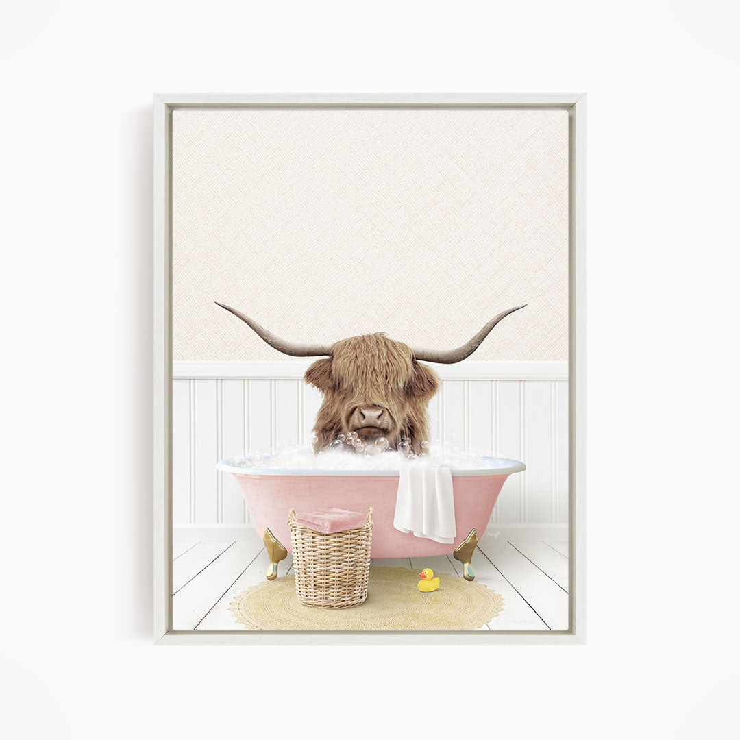 A brown cow with large horns is sitting in a pink bathtub filled with water, surrounded by a yellow rubber duck and a wicker basket.