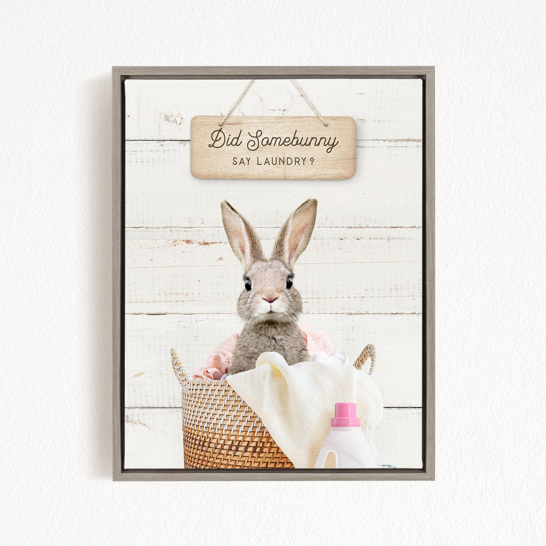 A cute rabbit sitting in a basket filled with laundry, with a sign above that says "Did Somebunny Say Laundry?".