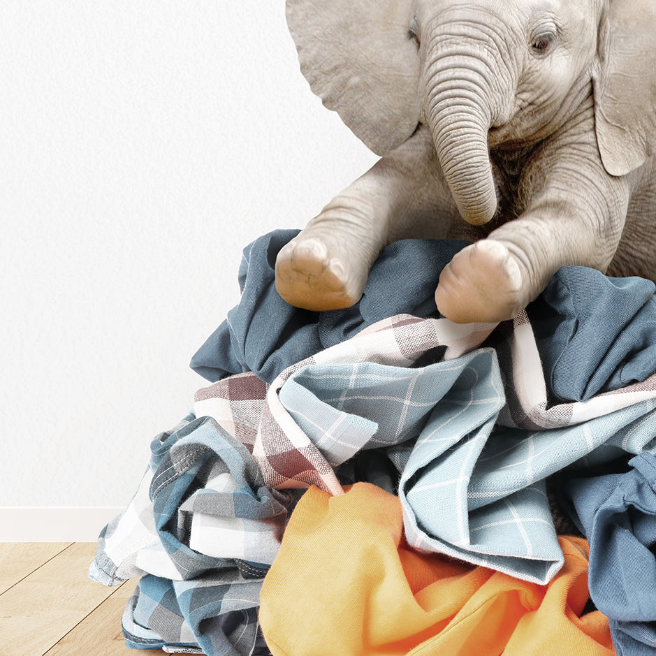 a stuffed elephant sitting on top of a pile of clothes