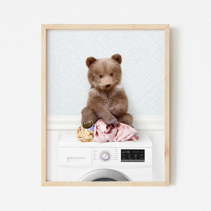 a brown bear sitting on top of a washing machine