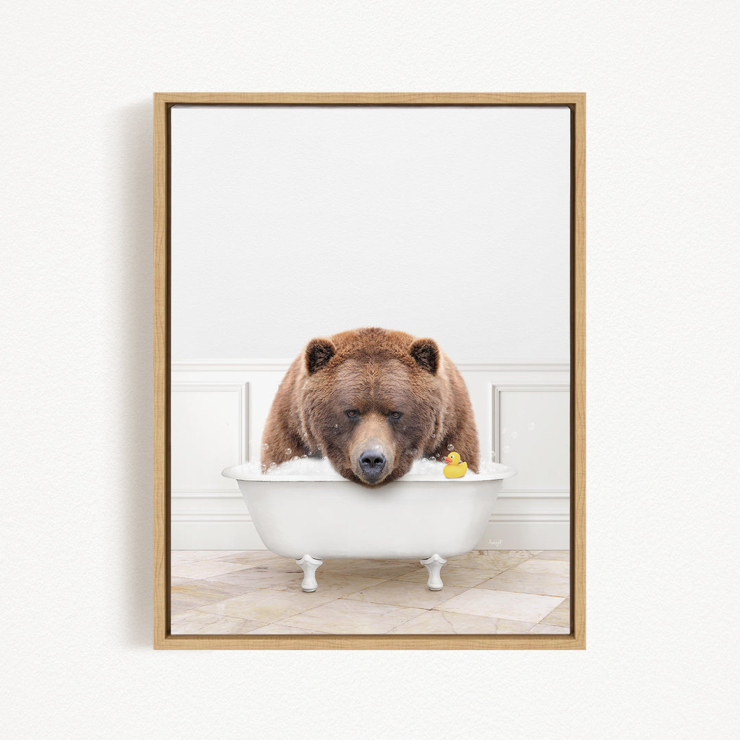 A brown bear is sitting in a white bathtub, with a rubber duck floating in the water.