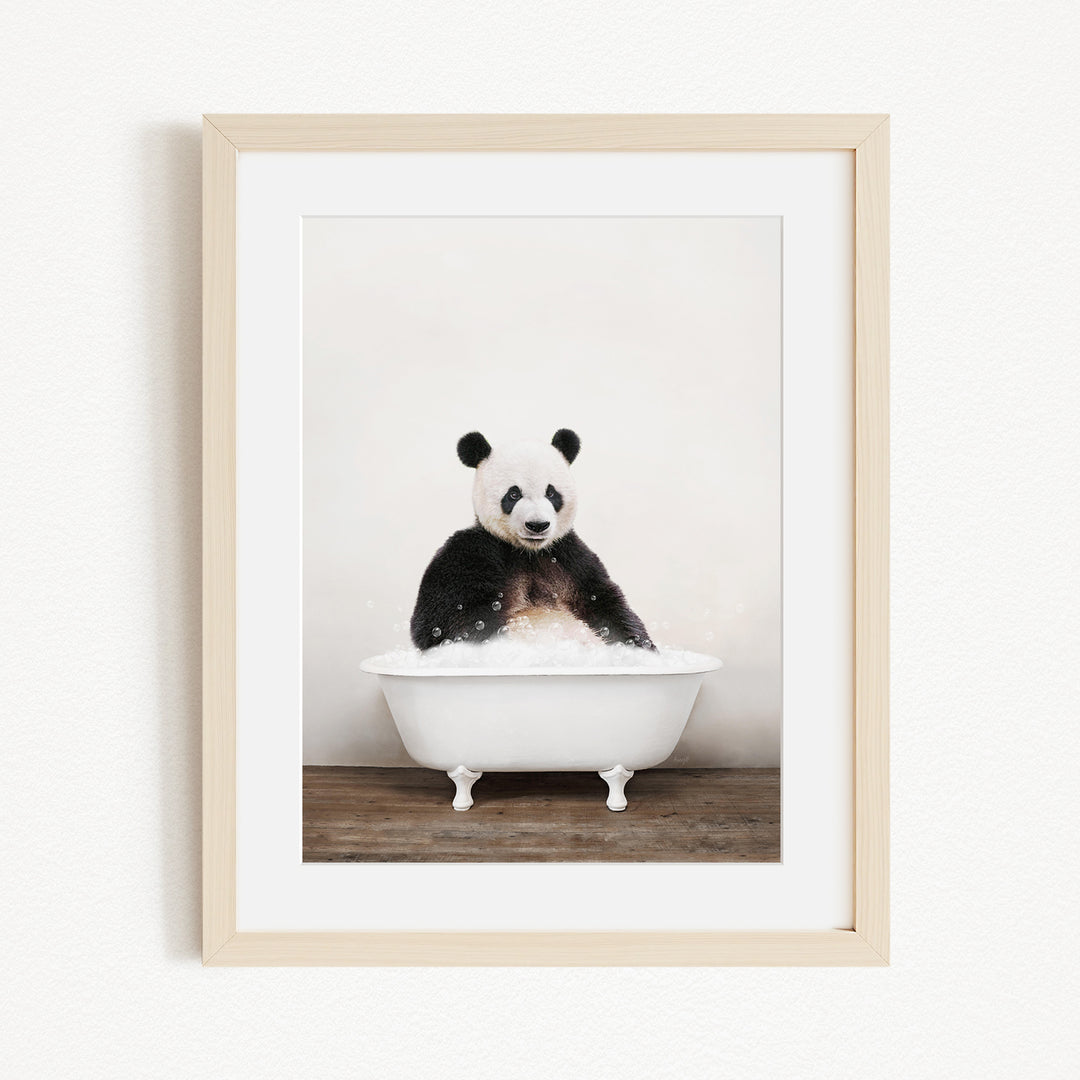 A panda bear sitting in a white bathtub filled with bubbles, looking directly at the camera.