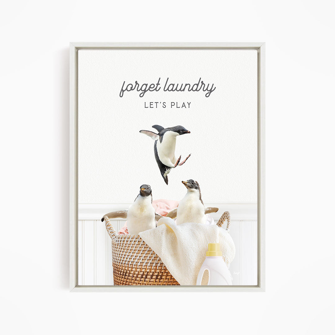 three penguins sitting in a basket filled with laundry, with one penguin jumping out of the basket.
