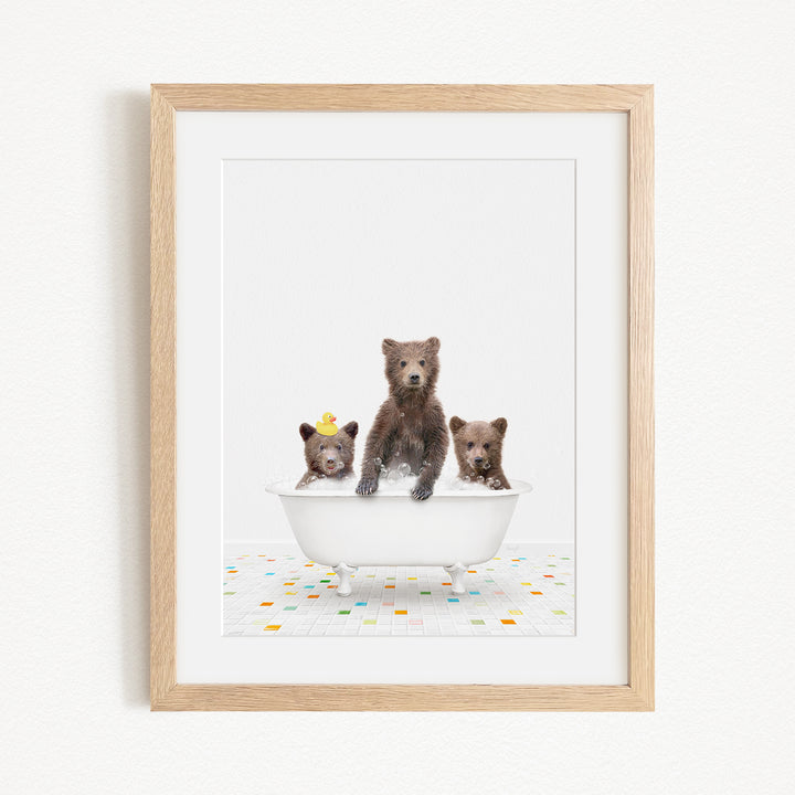 A framed image depicting three bears sitting in a white bathtub, with one bear wearing a yellow hat.