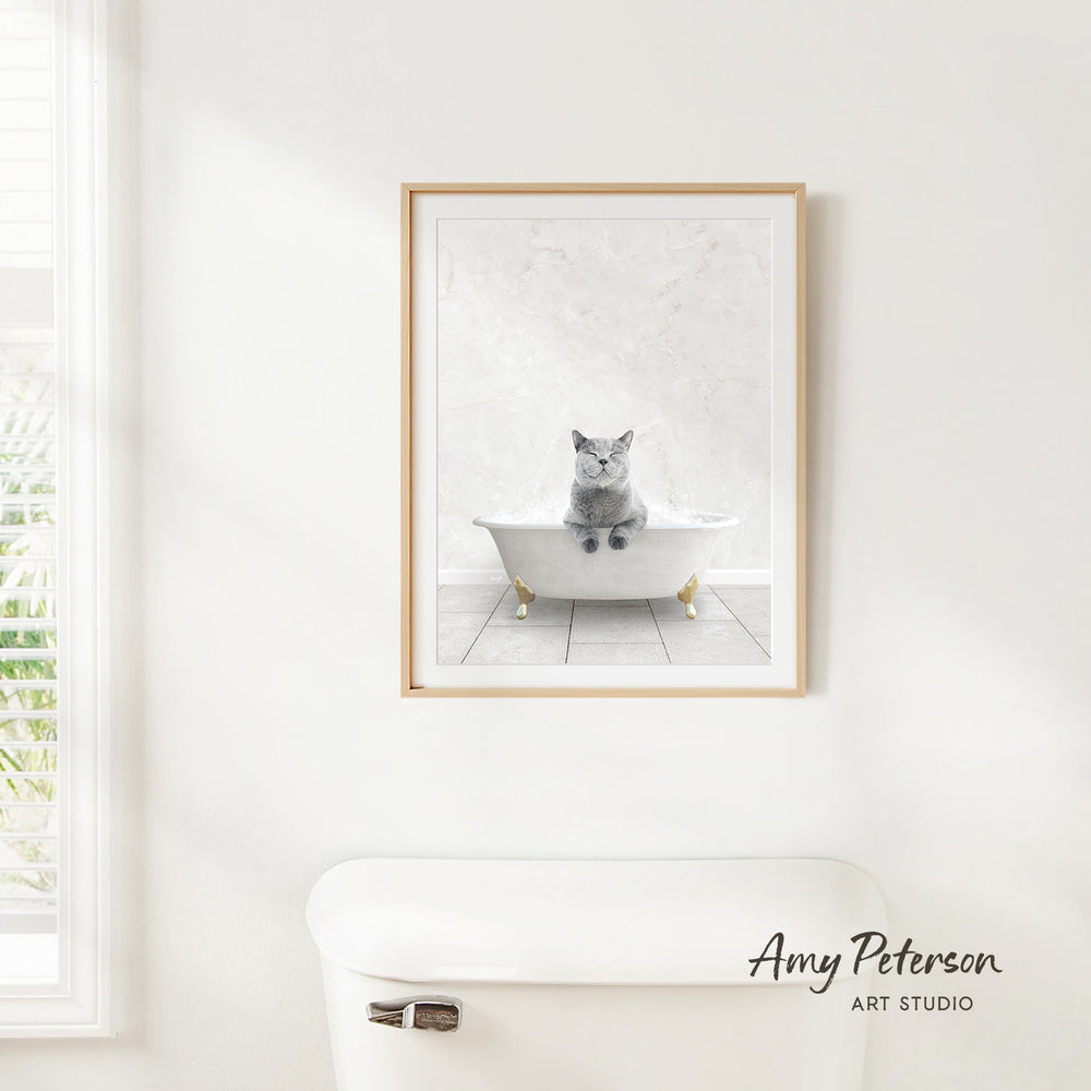A framed image of a cat sitting in a bathtub, with a white toilet visible in the background.