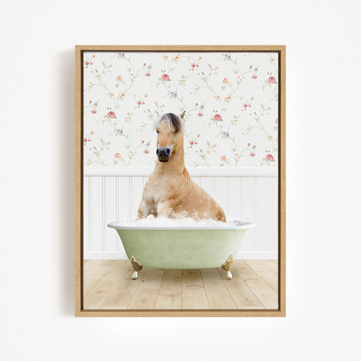 A light brown horse is sitting in a green bathtub filled with water, surrounded by a floral wallpaper.