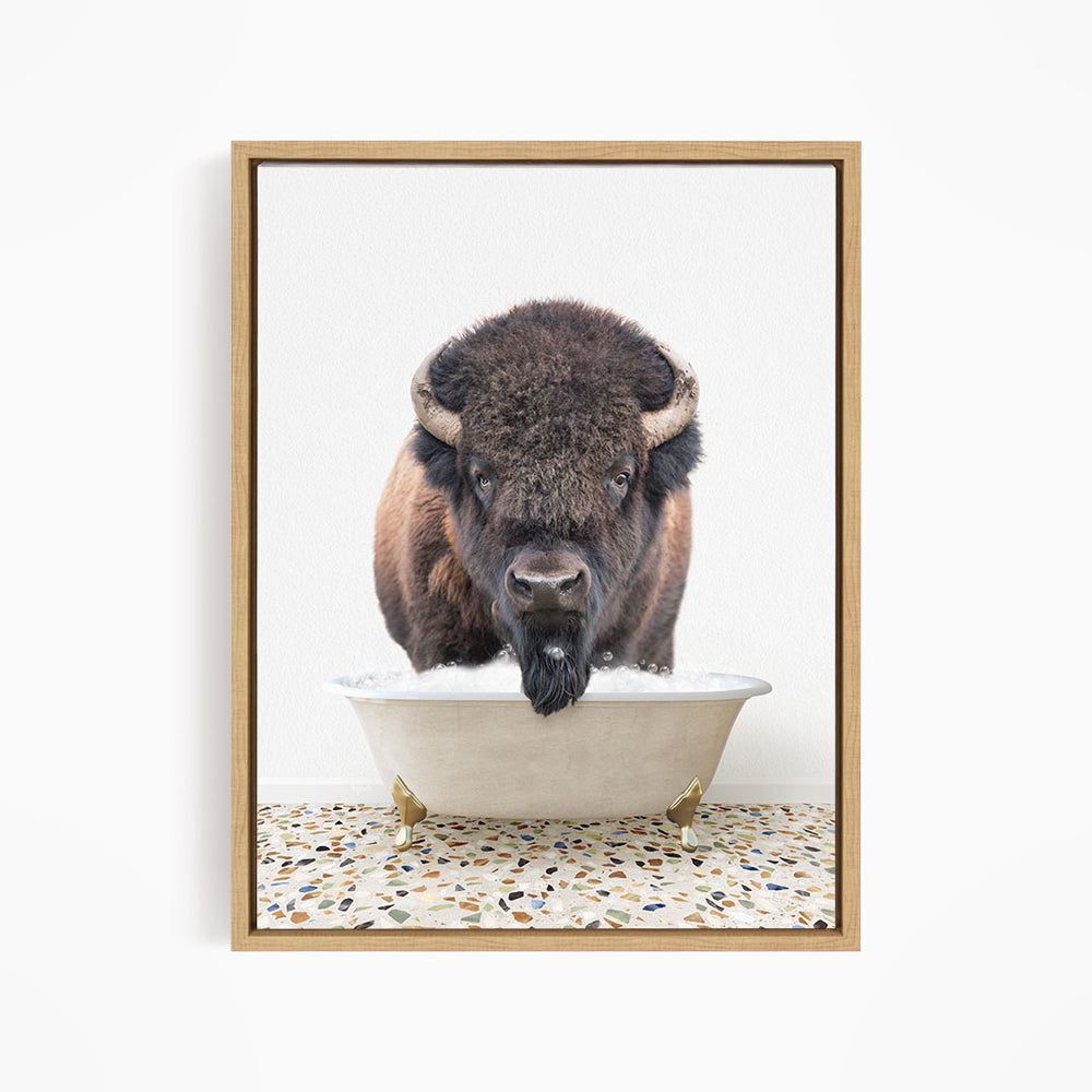 A bison with large horns is standing in a white bathtub filled with water, appearing to be enjoying a bath.