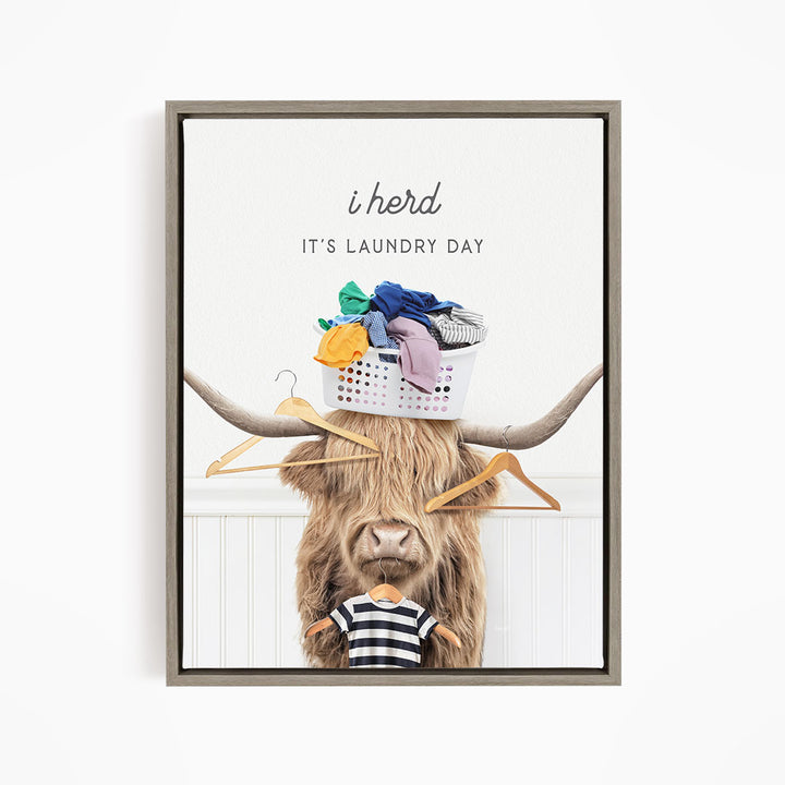 A framed image depicting a cow with a basket of laundry on its head, accompanied by the text "It's Laundry Day" and a humorous caption.