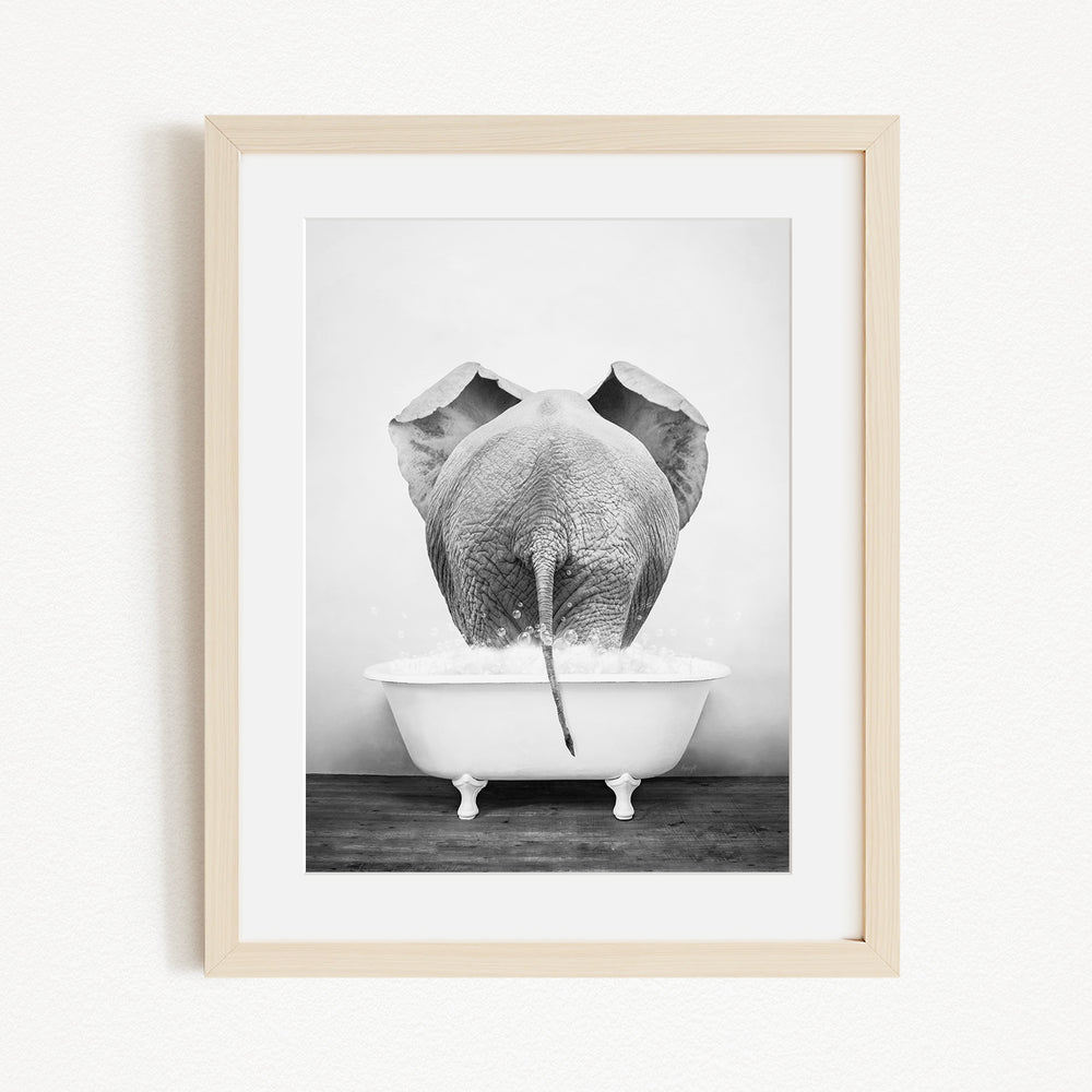 A black and white photograph of an elephant standing in a bathtub filled with water.