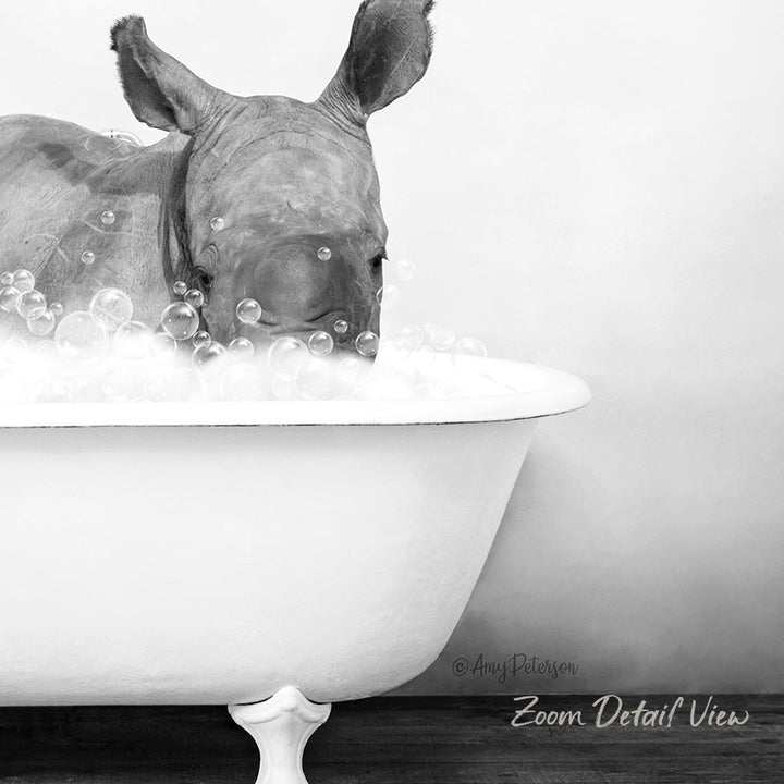 A rhinoceros is sitting in a bathtub filled with bubbles, enjoying a relaxing bath.