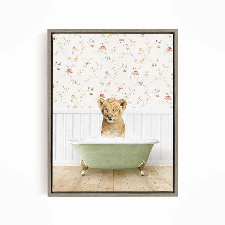 A young lion cub sitting in a green bathtub filled with water, with a floral wallpaper in the background.