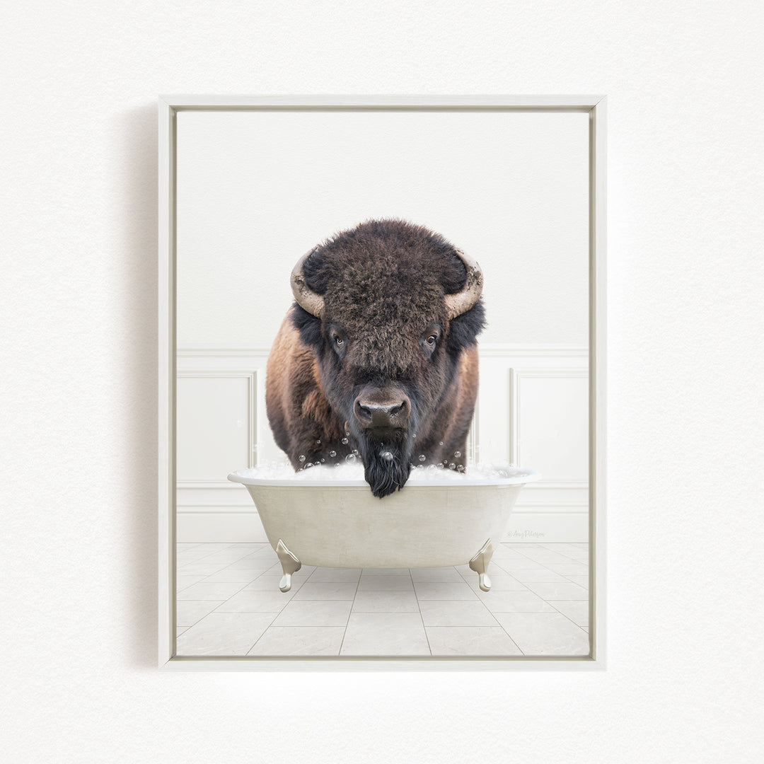 A buffalo with a long, shaggy mane is standing in a white bathtub filled with water, appearing to be enjoying a bath.