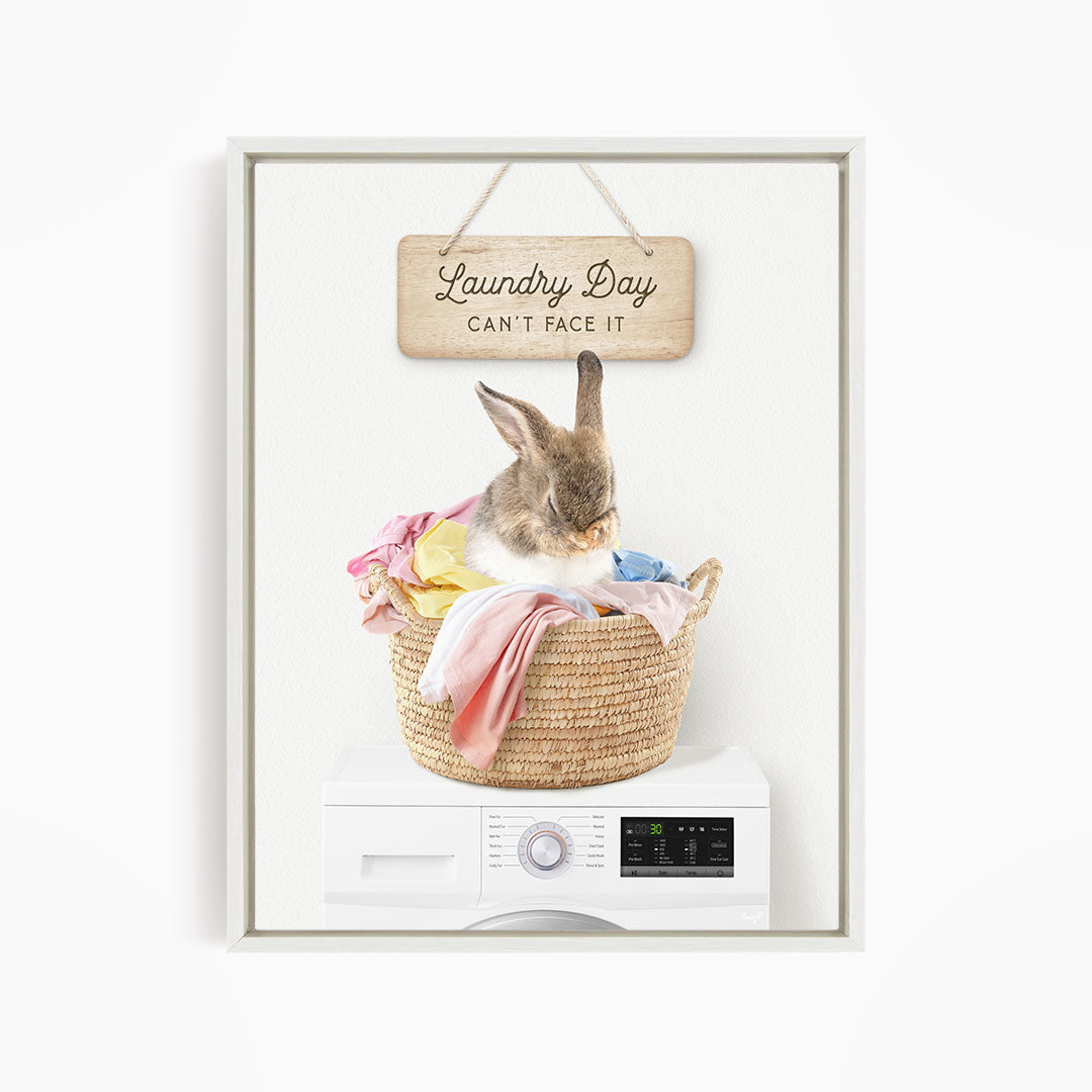A cute rabbit sitting in a woven laundry basket, with a sign above that says "Laundry Day Can't Face It".