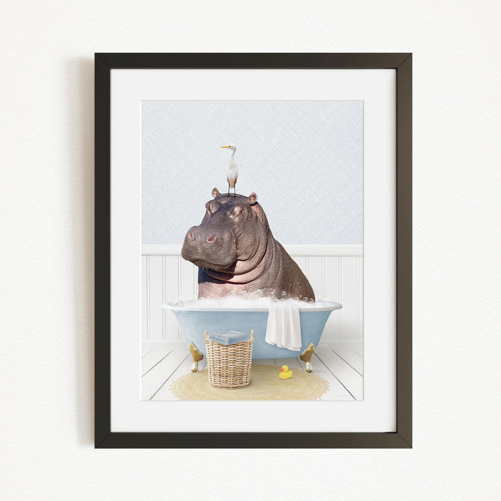 A framed image depicting a hippopotamus sitting in a bathtub, with a bird perched on its head.