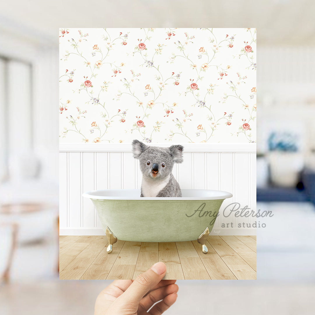 a hand holding a photo of a koala in a bathtub