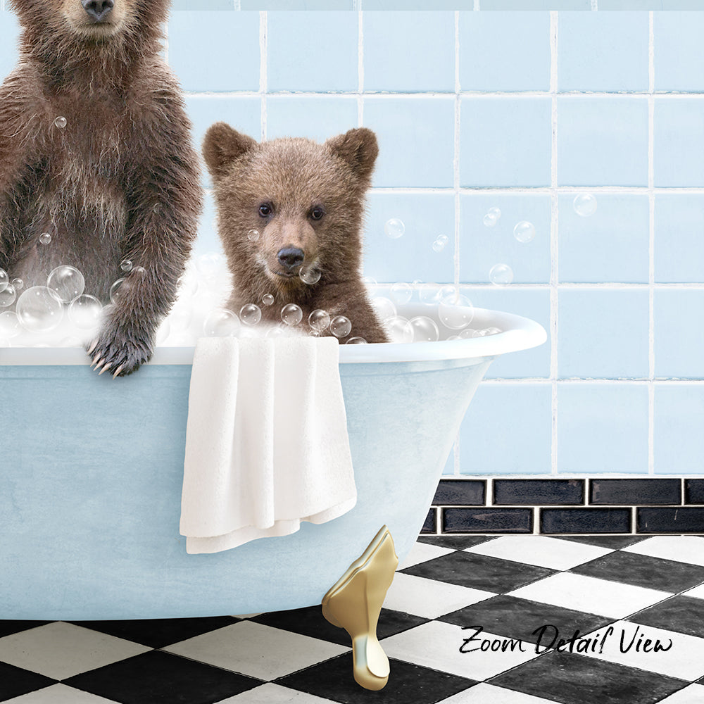 A baby bear sitting in a bathtub, surrounded by bubbles, with a towel draped over its head.