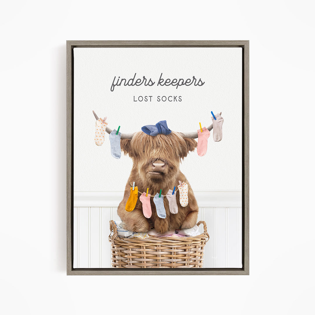 A brown cow sitting in a wicker basket filled with colorful socks, with the text "finders keepers" and "lost socks" displayed above the image.