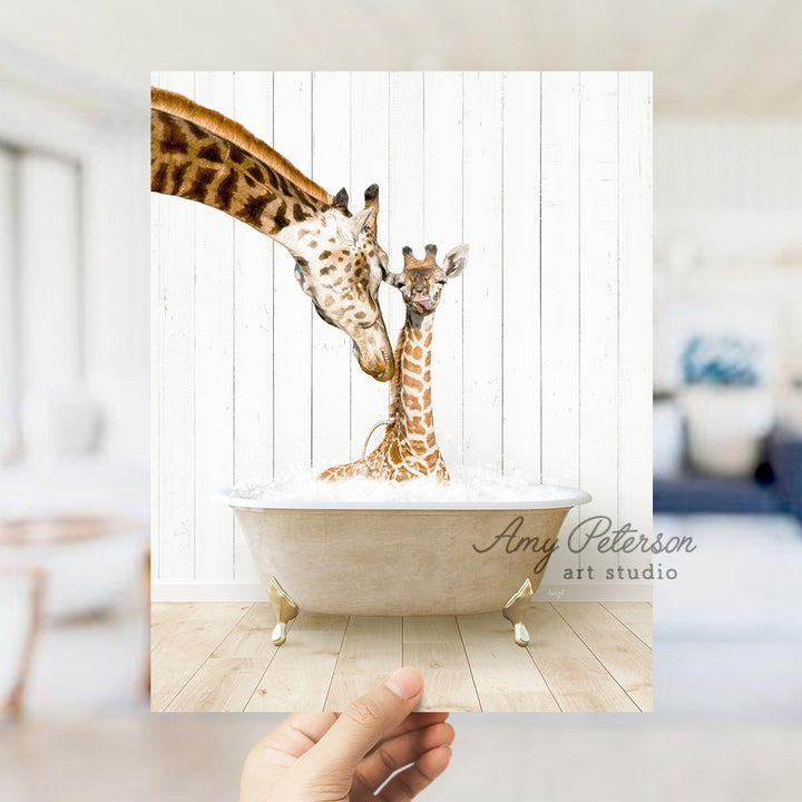 a hand holding up a picture of two giraffes in a bathtub