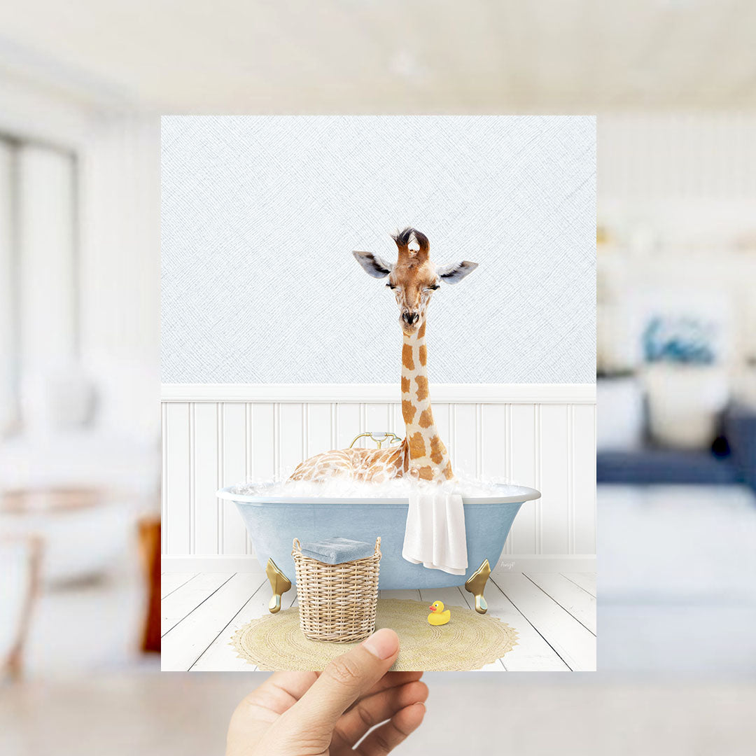A giraffe sitting in a bathtub filled with bubbles, surrounded by a yellow rubber duck and a wicker basket.