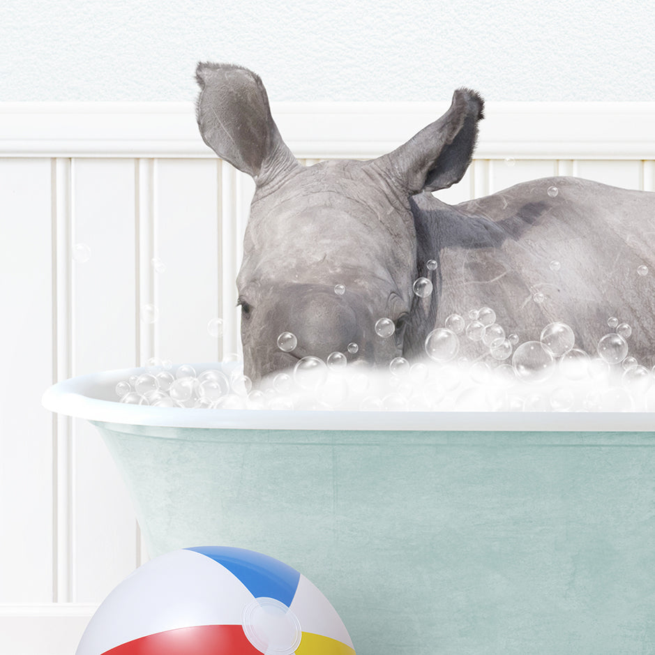 a rhino in a bathtub with bubbles and a beach ball