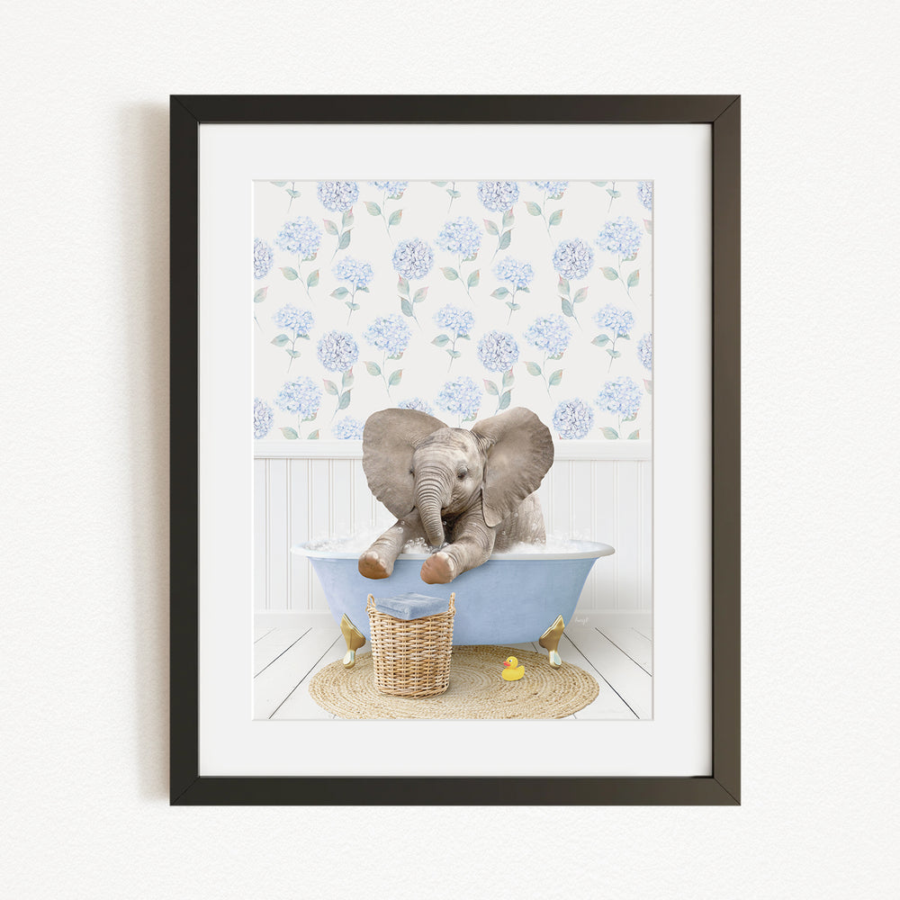 A baby elephant sitting in a blue bathtub, surrounded by a floral patterned wall and a basket of rubber ducks.