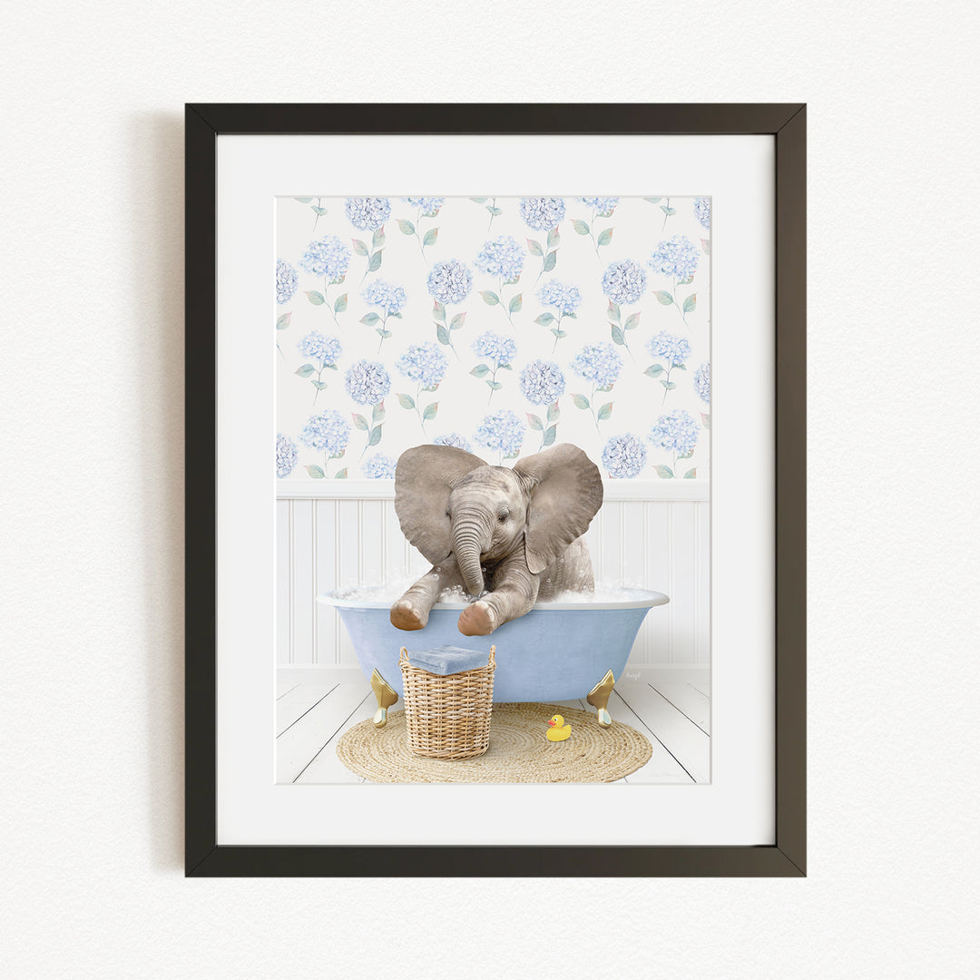 A baby elephant sitting in a blue bathtub, surrounded by a floral patterned wall and a basket of rubber ducks.