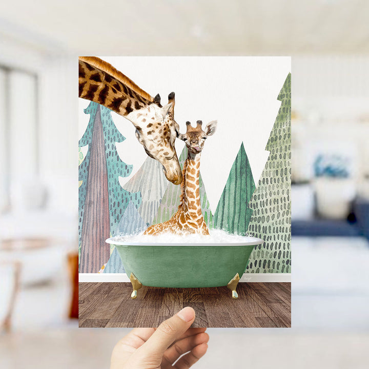 A hand holds up a framed image depicting two giraffes in a bathtub, surrounded by a forest-themed background.