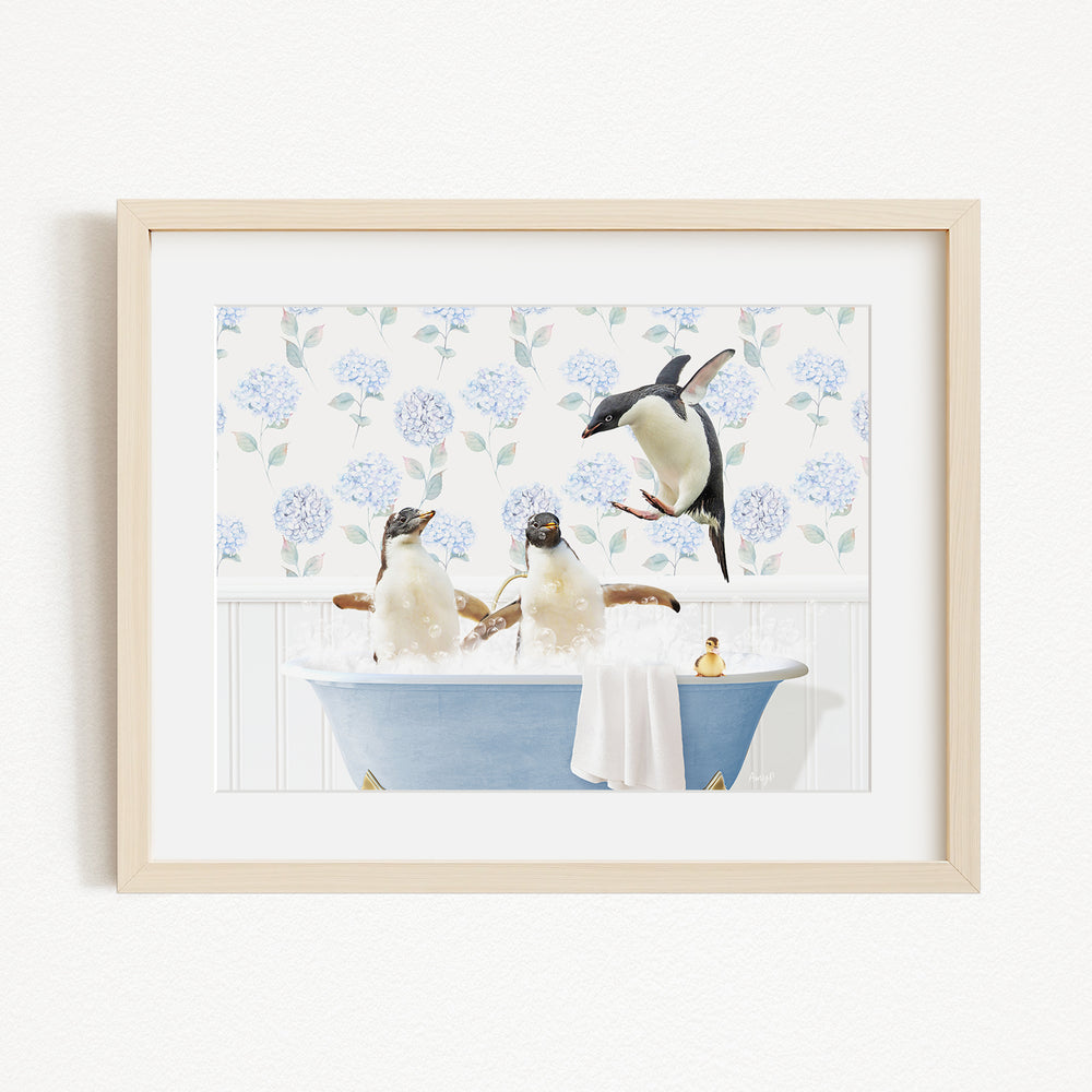 A framed image depicting three penguins sitting in a blue bathtub, with one penguin standing on the edge of the tub and another penguin sitting inside the tub.