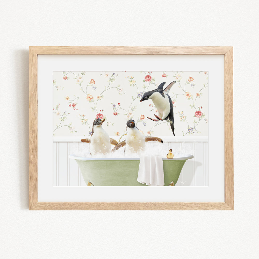 A framed image depicting three penguins sitting in a green bathtub, with one penguin standing on the edge of the tub and another sitting inside.