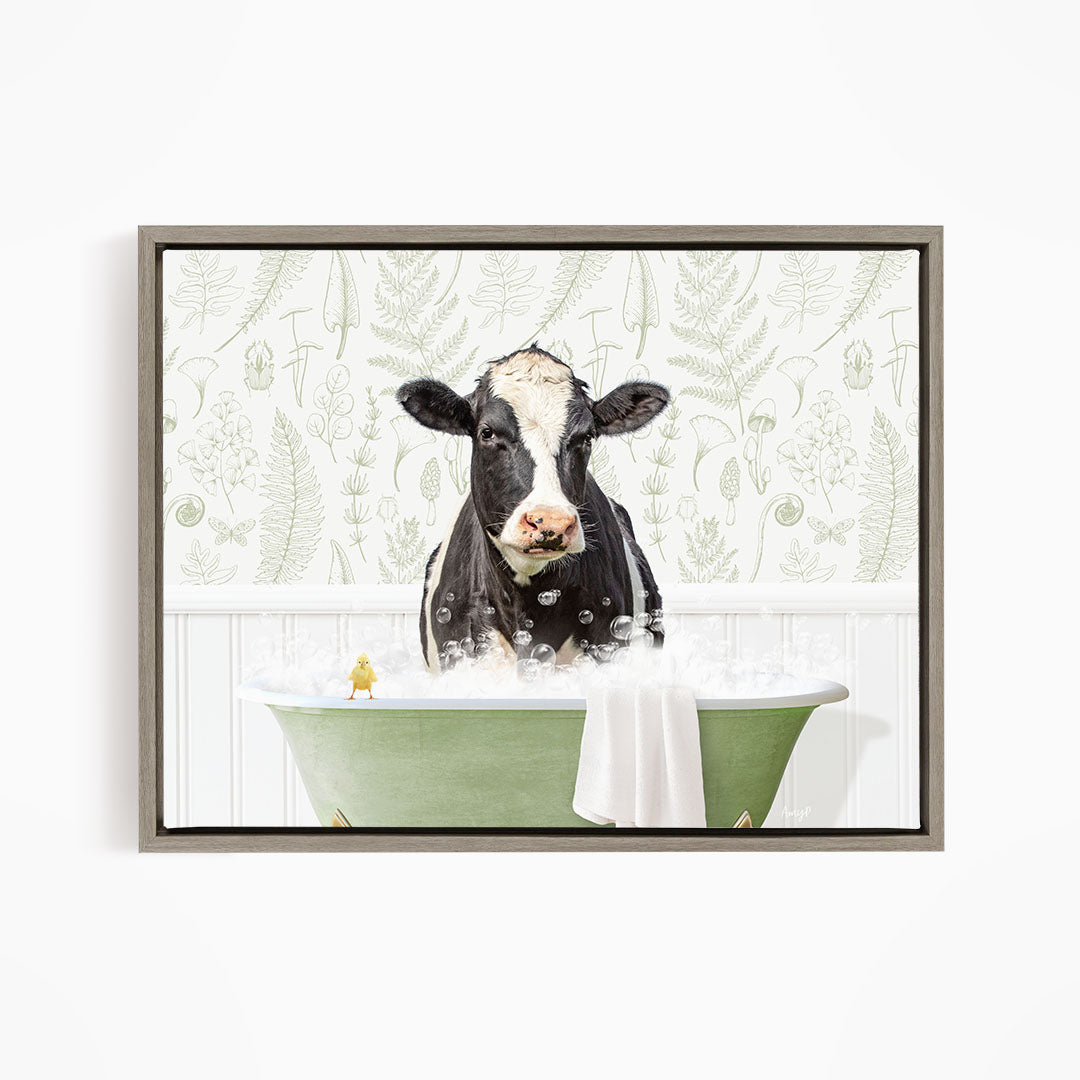 A black and white cow is sitting in a green bathtub filled with bubbles, with a yellow bird perched on the edge of the tub.