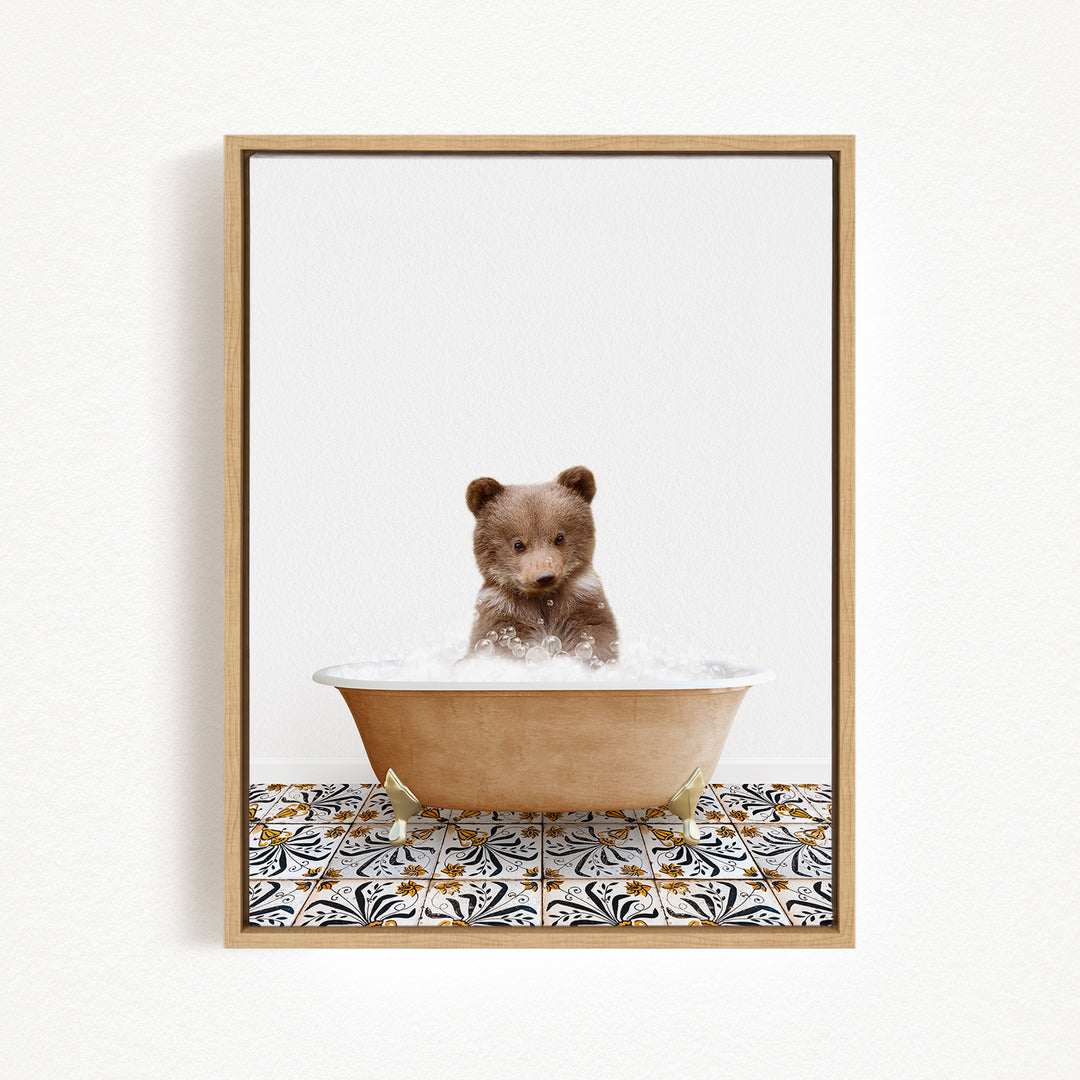 A cute brown bear cub sitting in a bathtub filled with bubbles, surrounded by a patterned tile floor.