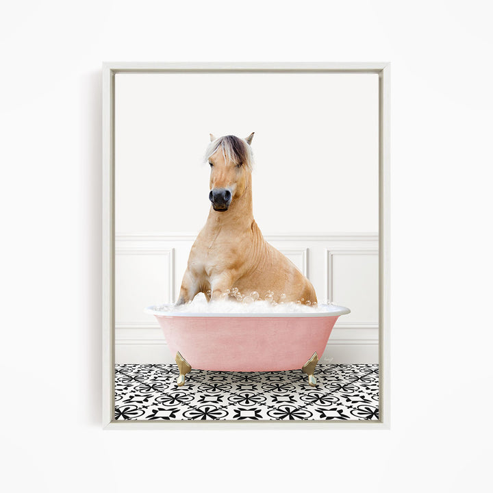 A light brown horse is sitting in a pink bathtub filled with water, surrounded by a black and white patterned floor.