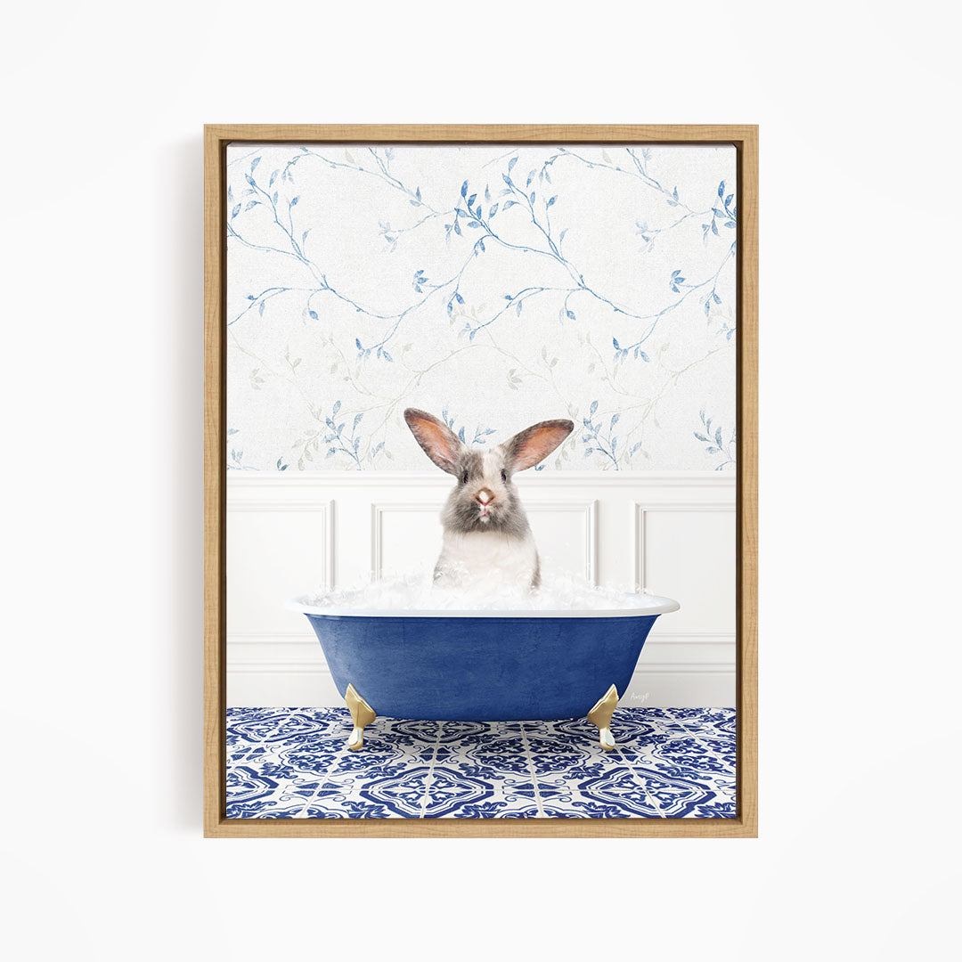 A white rabbit with brown ears is sitting in a blue bathtub filled with water, surrounded by a blue and white patterned rug.