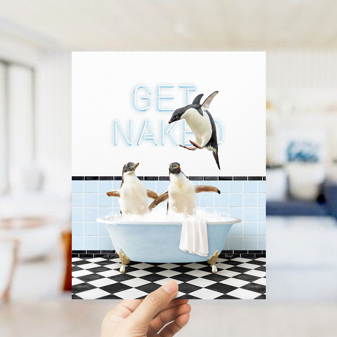 A hand holding a framed image of two penguins sitting in a bathtub, with one penguin flying out of the tub and the other penguin sitting in the tub.