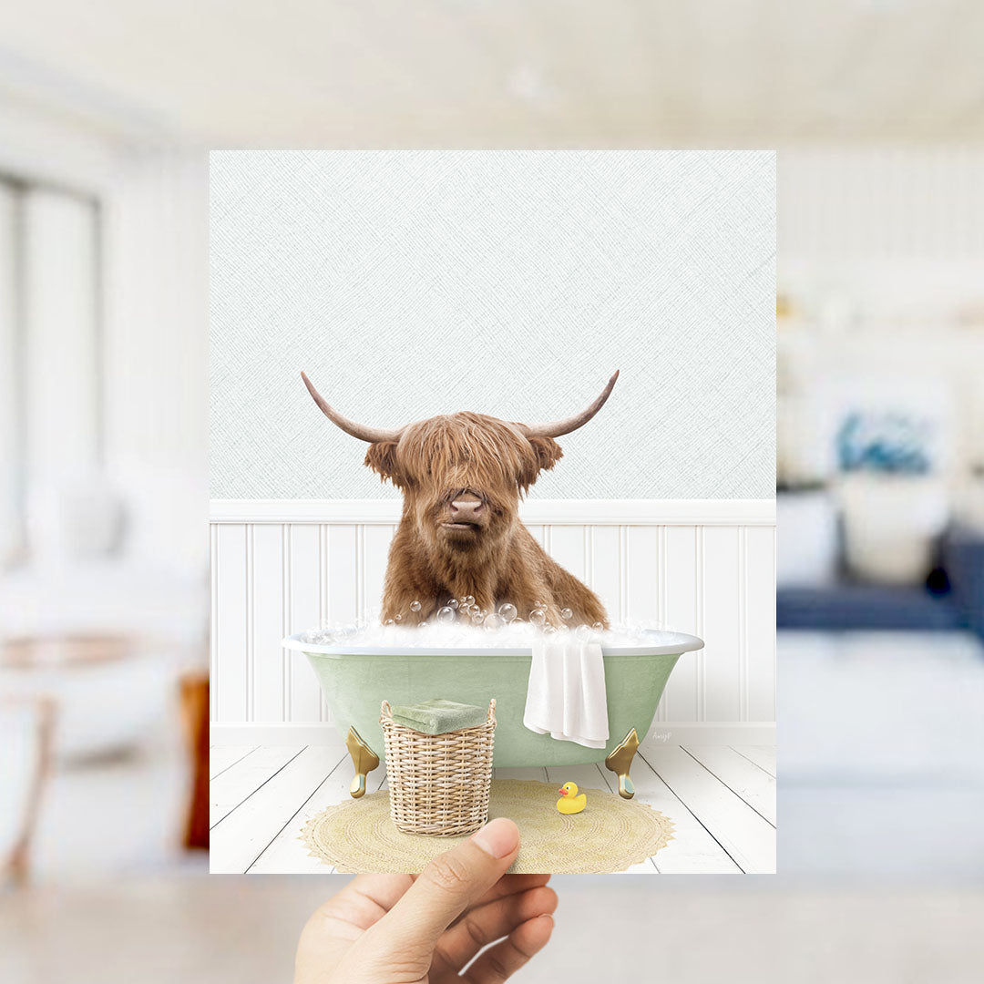 A brown cow with long horns is sitting in a green bathtub filled with bubbles, surrounded by a yellow rubber duck and a white towel.