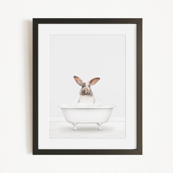 A white rabbit sitting in a white bathtub filled with bubbles, looking directly at the camera.