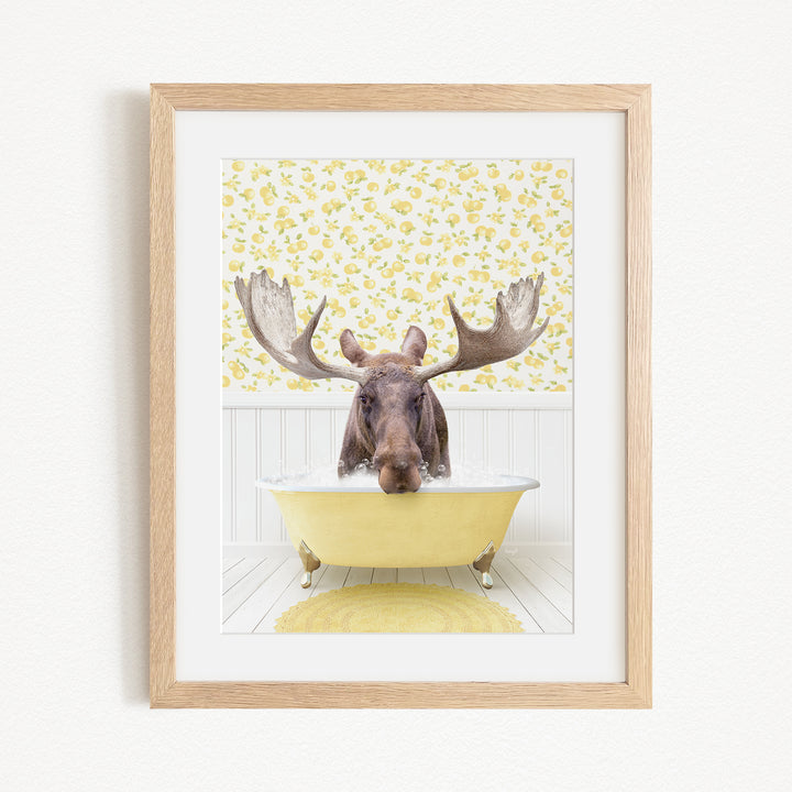 A moose with large antlers is sitting in a yellow bathtub, surrounded by a yellow and white floral pattern on the wall behind it.