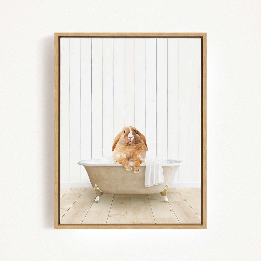 A brown rabbit sitting in a white bathtub filled with water, with a towel draped over the side of the tub.