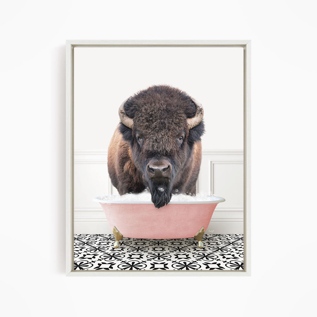 A buffalo with large horns is standing in a pink bathtub filled with water, creating a whimsical and humorous scene.