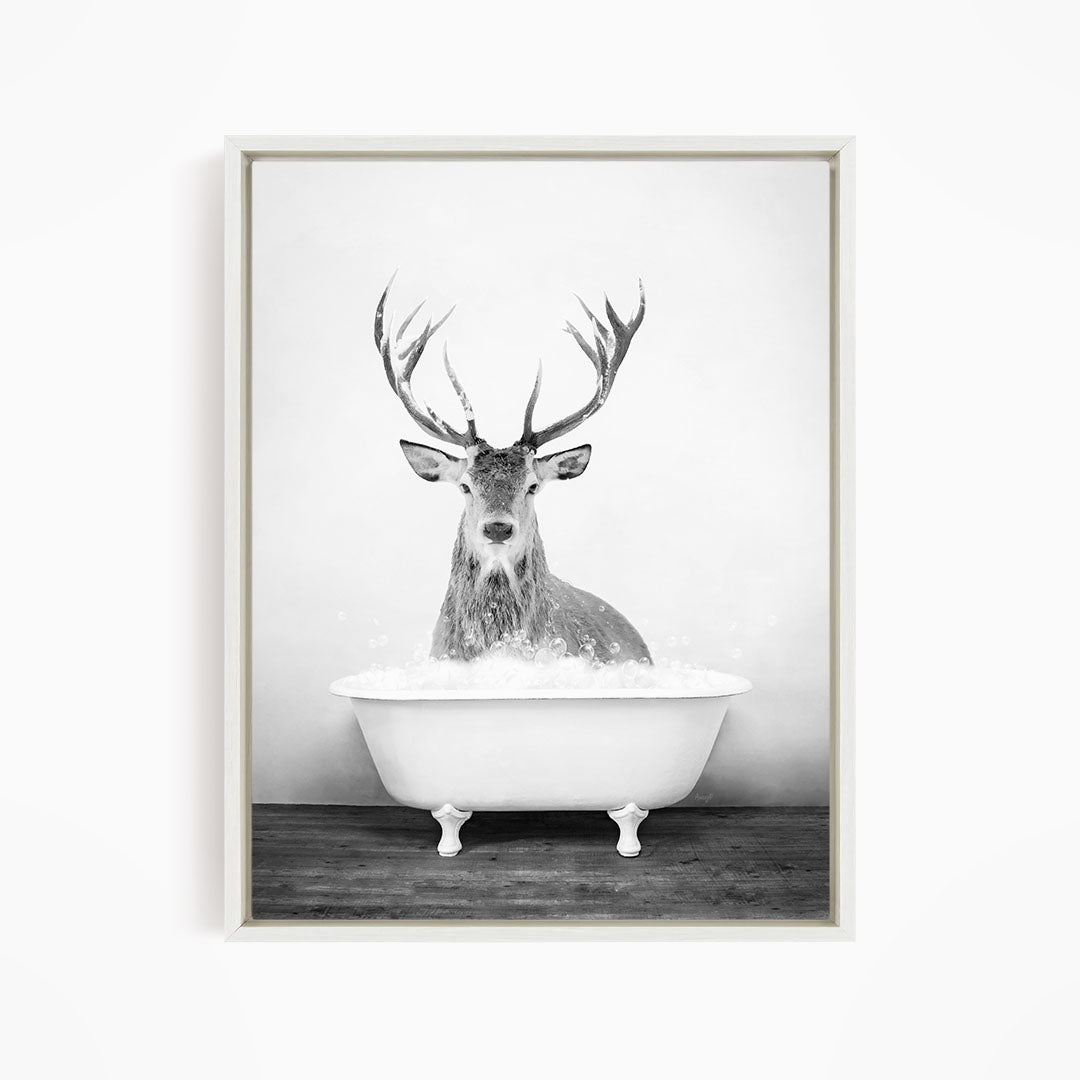 A deer with large antlers is sitting in a white bathtub filled with water, creating a whimsical and unexpected scene.